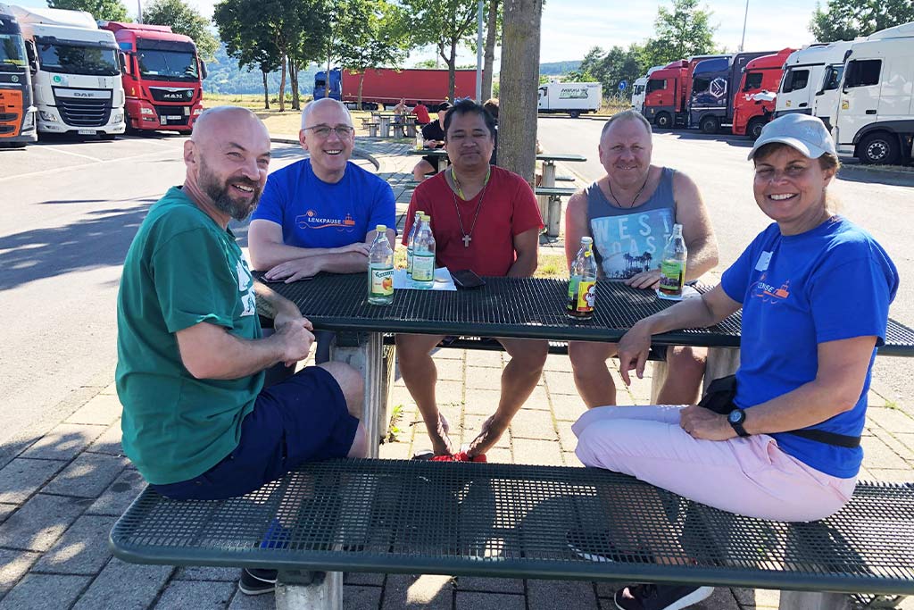 Das Team der Lenkpause im Gespräch mit LKW-Fahrern auf einem Rastplatz. Foto: Betriebsseelsorge Bodensee-Hohenzollern, Erzdiözese Freiburg